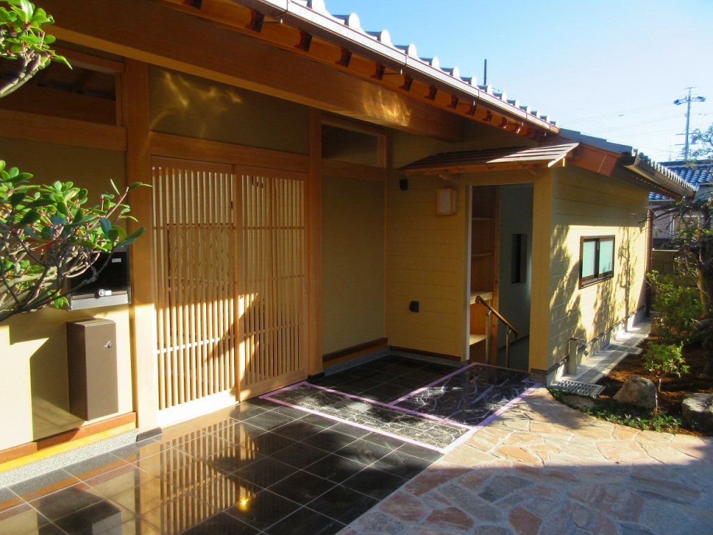 本宅へと続く石畳のアプローチ。格式ある門、そして車庫。【やねきハウスの新築注文住宅】：外観